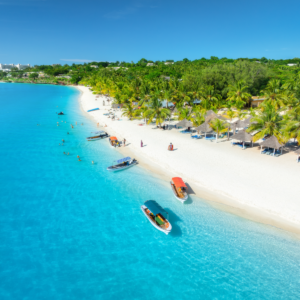 Aerial view of the boats on tropical sea coast with white sandy beach at sunset. Summer holiday in Kendwa, Zanzibar. Landscape w
